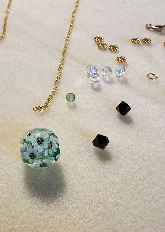 a soft mat hold the chain and beads that will be made into a necklace